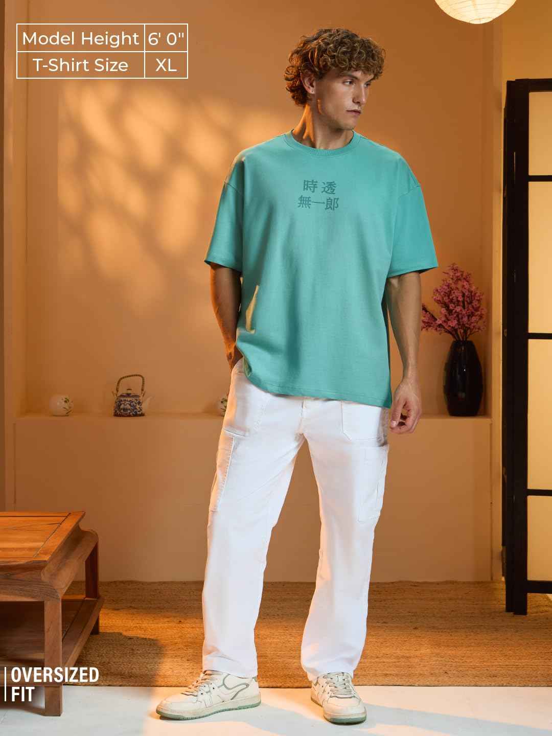 Model wearing an oversized fit Demon Slayer Muichiro T-shirt in teal with white pants indoors