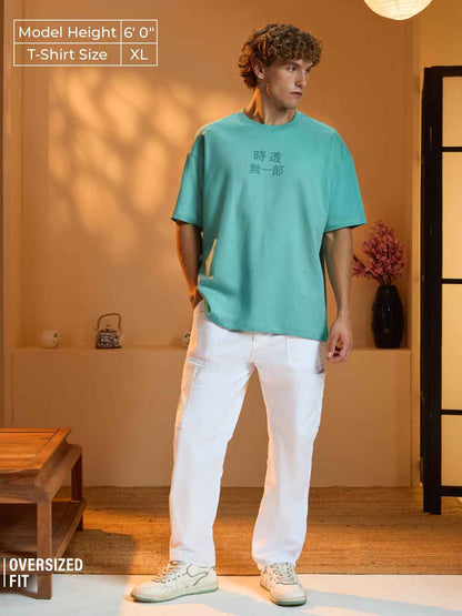 Model wearing an oversized fit Demon Slayer Muichiro T-shirt in teal with white pants indoors