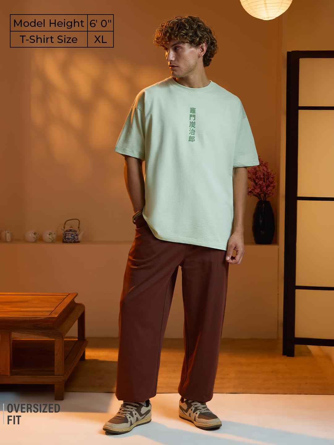 Model wearing an oversized fit Demon Slayer Tanjiro T-shirt in light green with brown pants