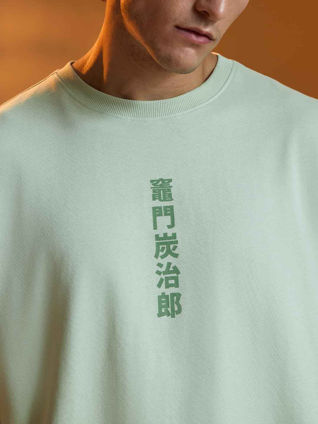 Close-up of a man wearing a light green Demon Slayer Tanjiro T-shirt with Japanese characters printed on the front