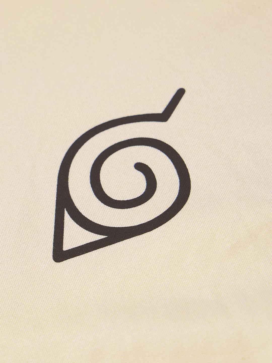 Close-up of black spiral leaf symbol printed on cream Naruto Shippuden oversized t-shirt fabric
