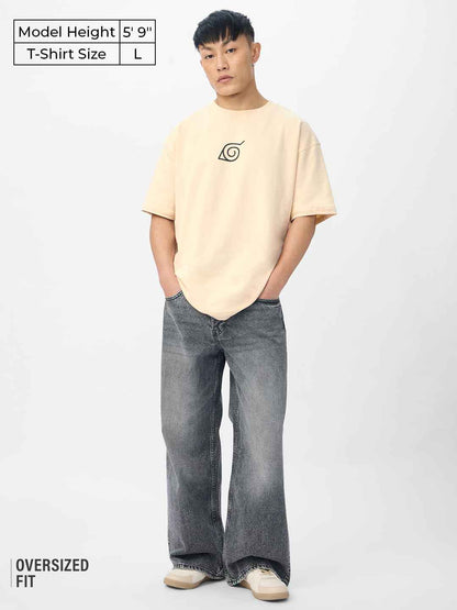 Man wearing Naruto Shippuden oversized t-shirt in beige with black symbol print and wide-leg jeans
